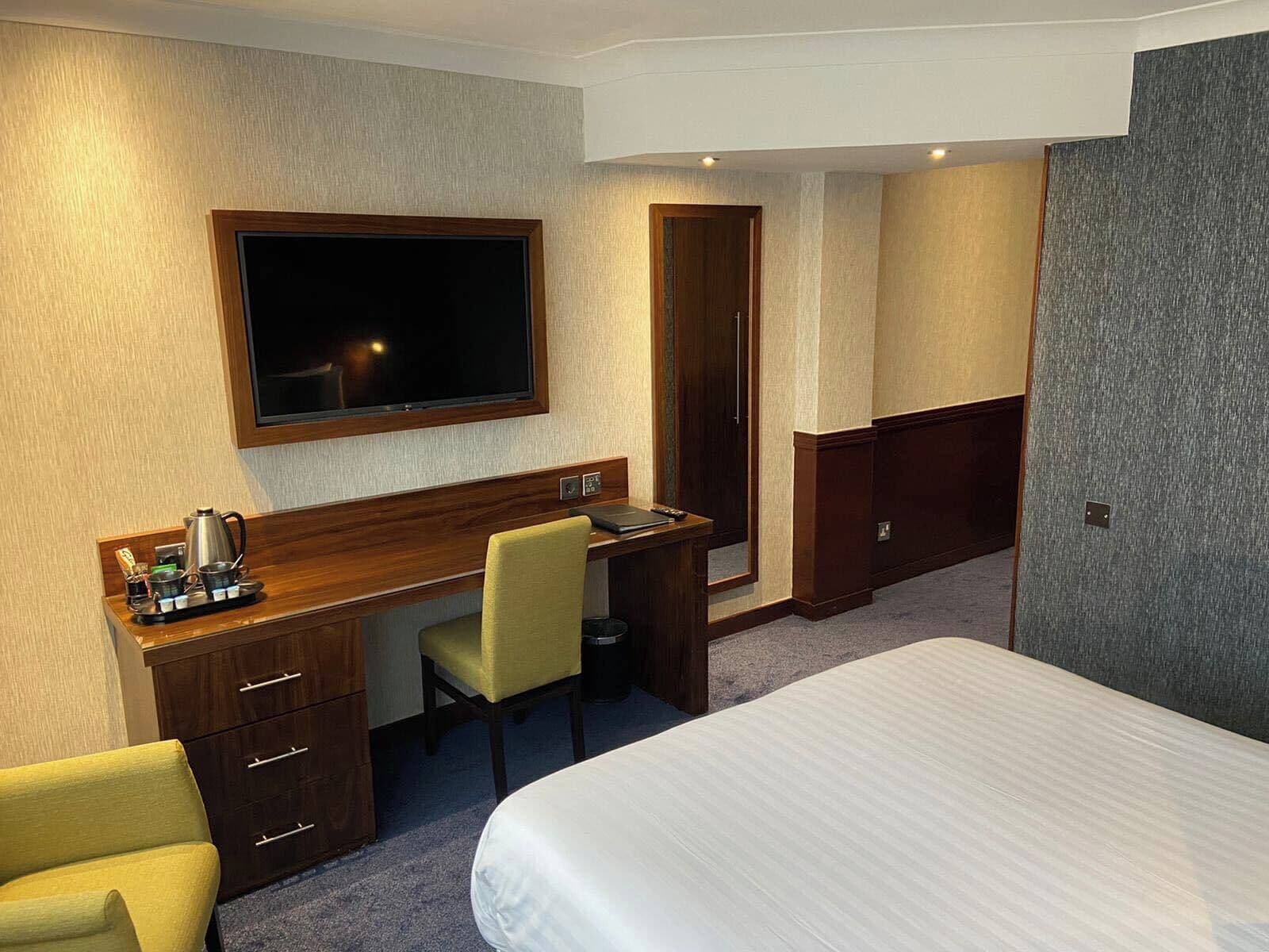 Une chambre d’hôtel comprenant un lit, un bureau avec une chaise, une télévision et un minibar.
