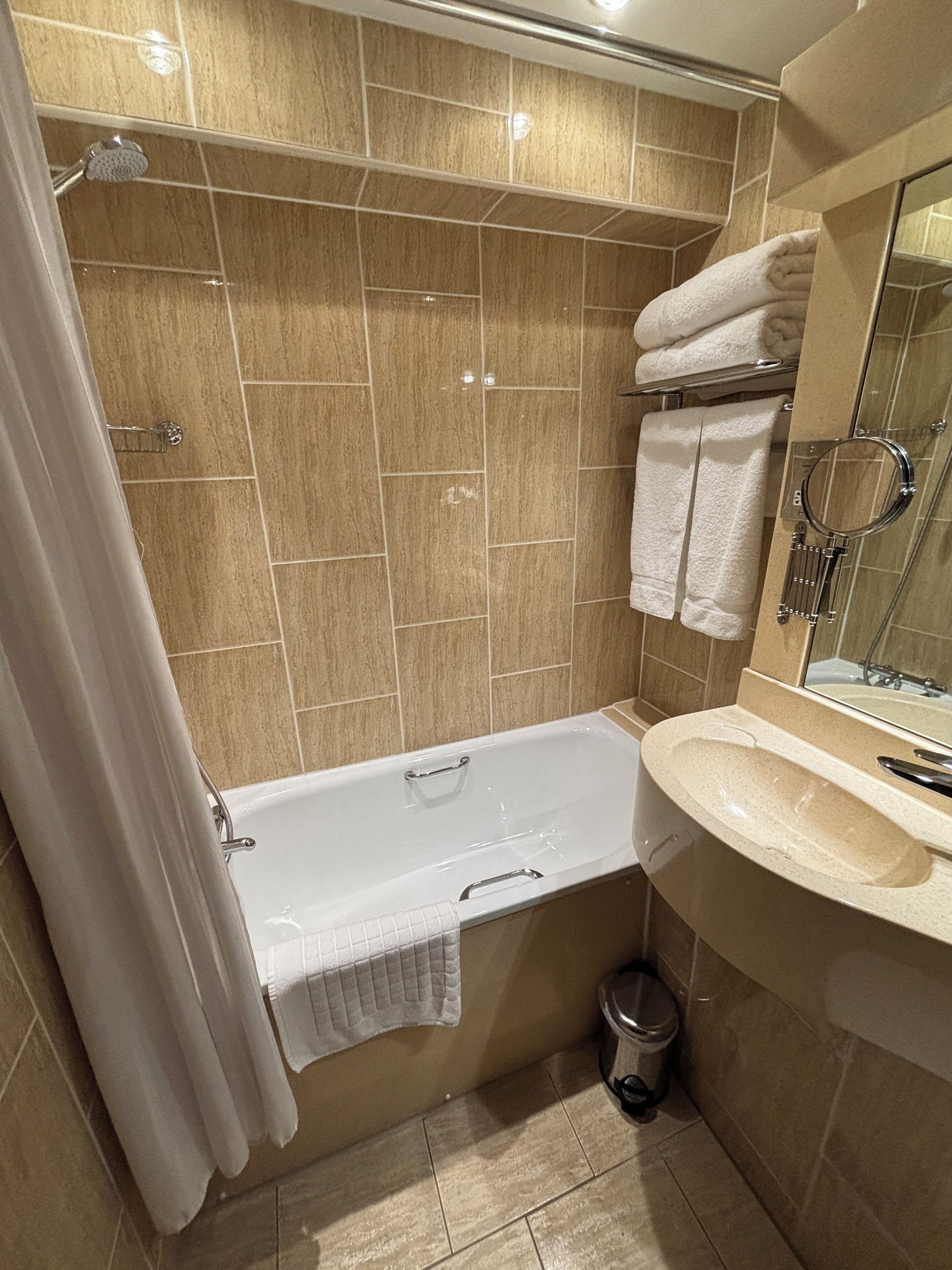 A bathroom with a bathtub, a sink, a mirror, and a shower.