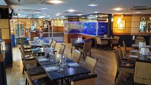 Un ristorante con diversi tavoli e sedie, un grande acquario e una zona bar.