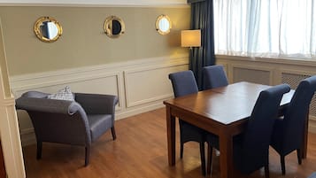 Una habitación con una mesa de comedor de madera, cuatro sillas, un sofá y tres espejos colgados en la pared.