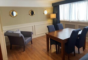 Una habitación con una mesa de comedor de madera, cuatro sillas, un sofá y tres espejos colgados en la pared.