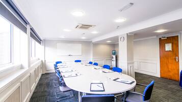 A conference room with a long table, blue chairs, and a clock on the wall.