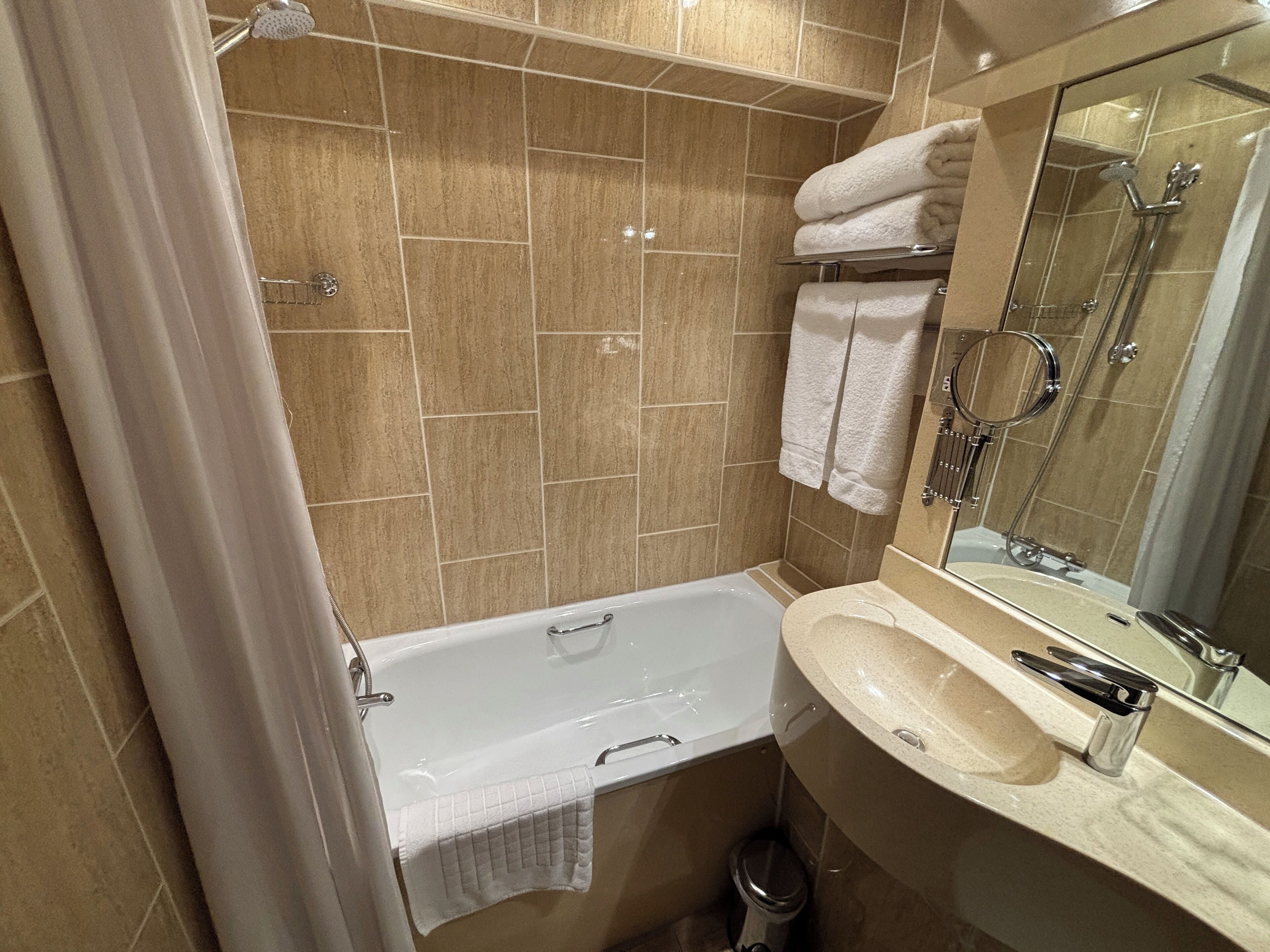A bathroom with a bathtub, a sink, a mirror, and a shower.