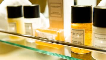 A glass shelf with various toiletries including a bottle labeled "Shower Gel."