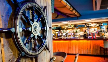 A bar with a wooden wheel and a bar counter.