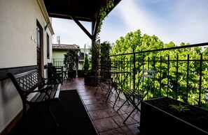 A balcony with a view of lush greenery, a wooden bench, and a table with chairs. - Kazimierz's Secret Apartments (Kraków)