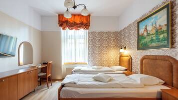 A hotel room with two beds, a desk, a chair, a television, and a painting on the wall.
