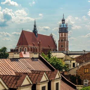 A historic building with a prominent tower and a large dome, surrounded by other buildings with red-tiled roofs. - Kazimierz's Secret Apartments (Kraków)