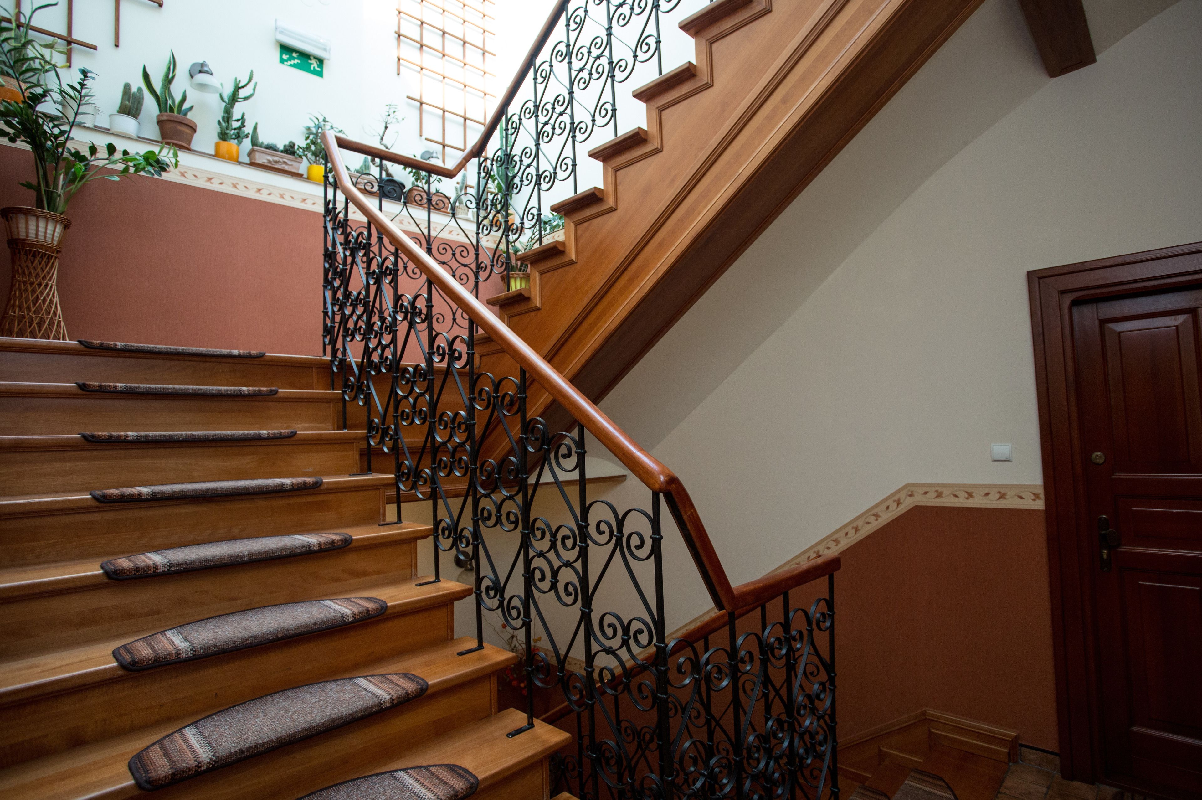 Una escalera de madera con barandales negros ornamentados y elegantes alfombrares.