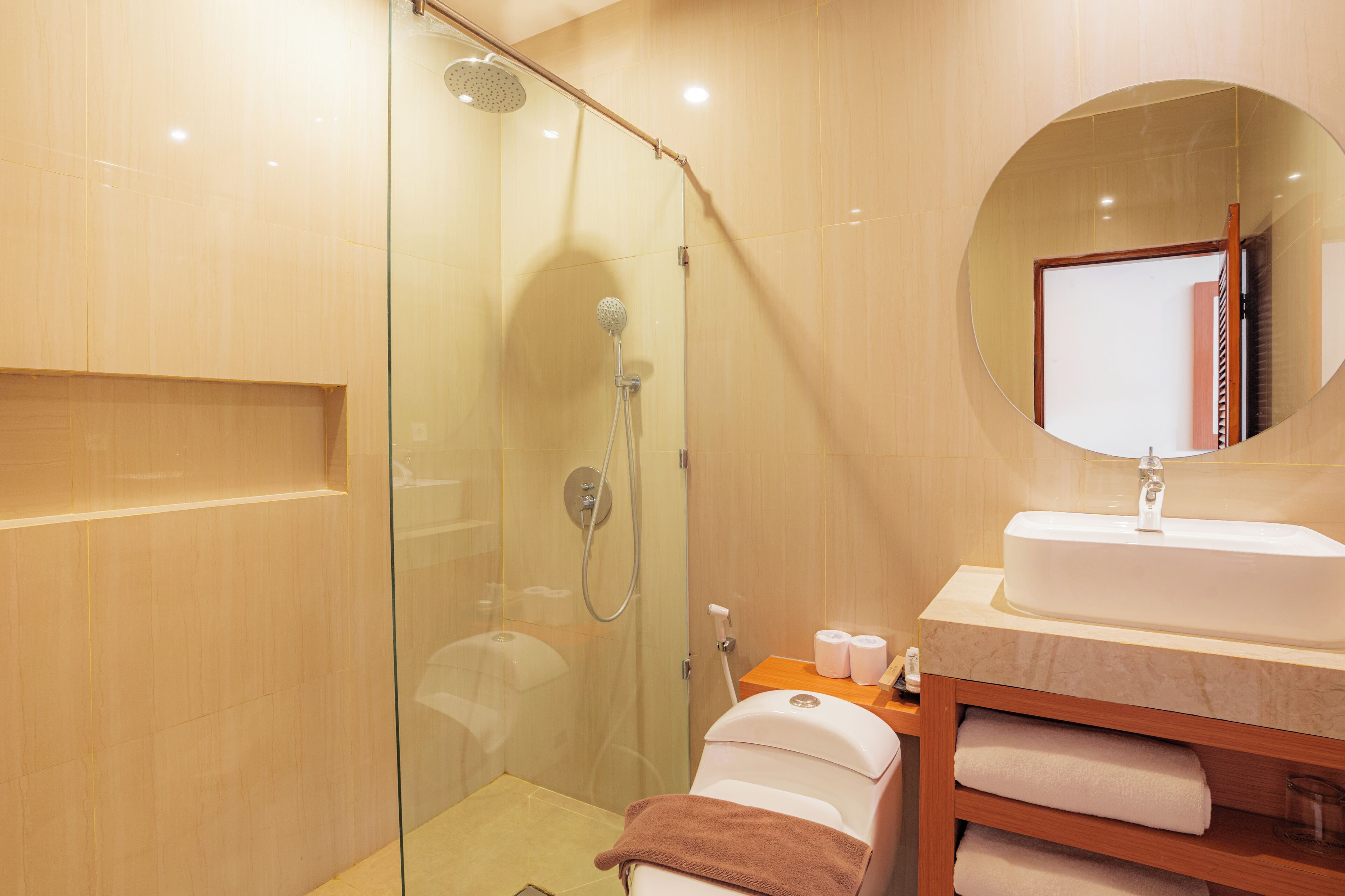 A modern bathroom with a glass shower enclosure, a sink with a mirror, and a wooden vanity with towels.