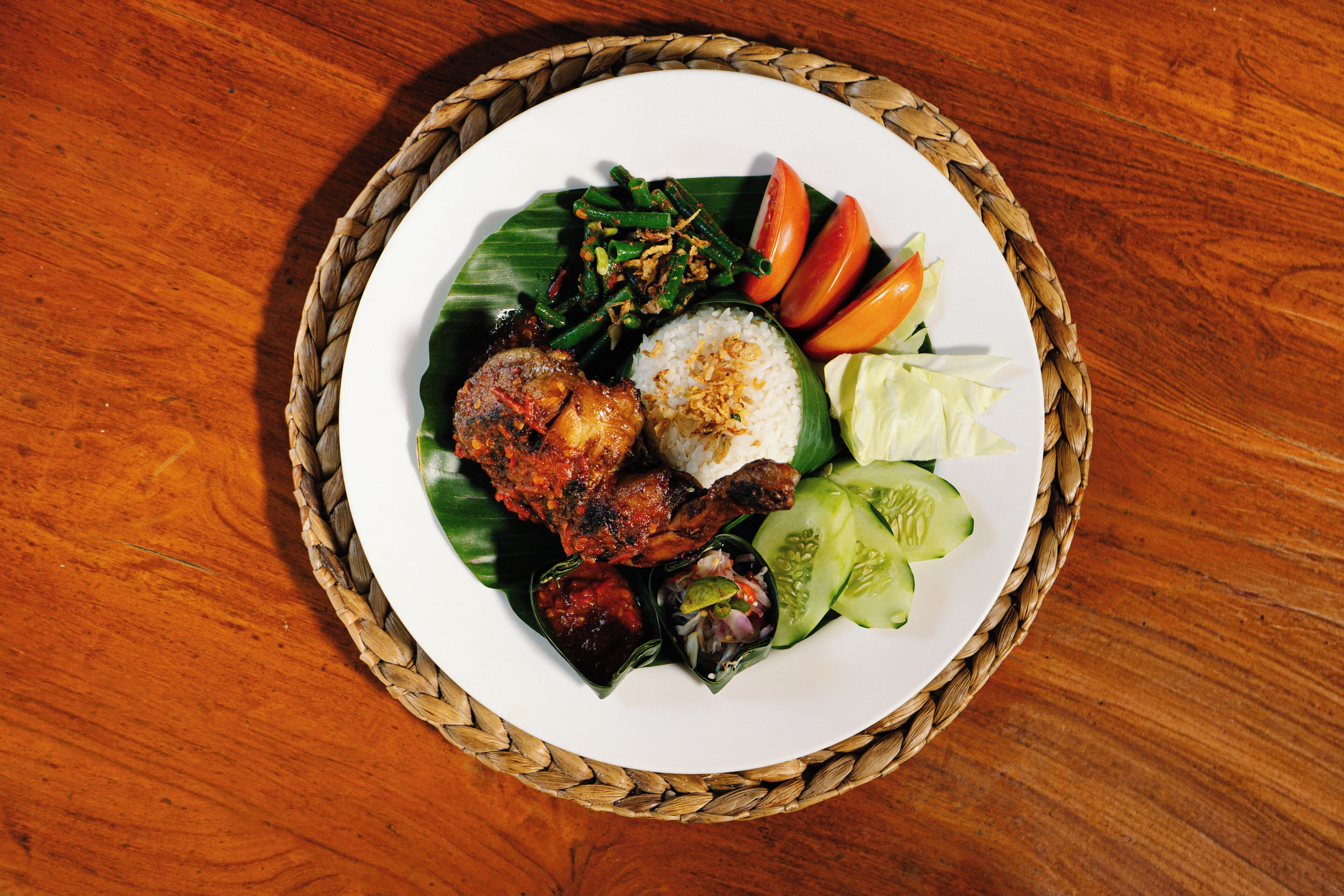 Une assiette de nourriture composée de riz, de légumes et de viande, le tout servi sur un napperon tissé.