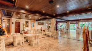 A spacious lobby with marble flooring, white wicker furniture, and a large decorative golden statue. - Wina Holiday Villa (Kuta)