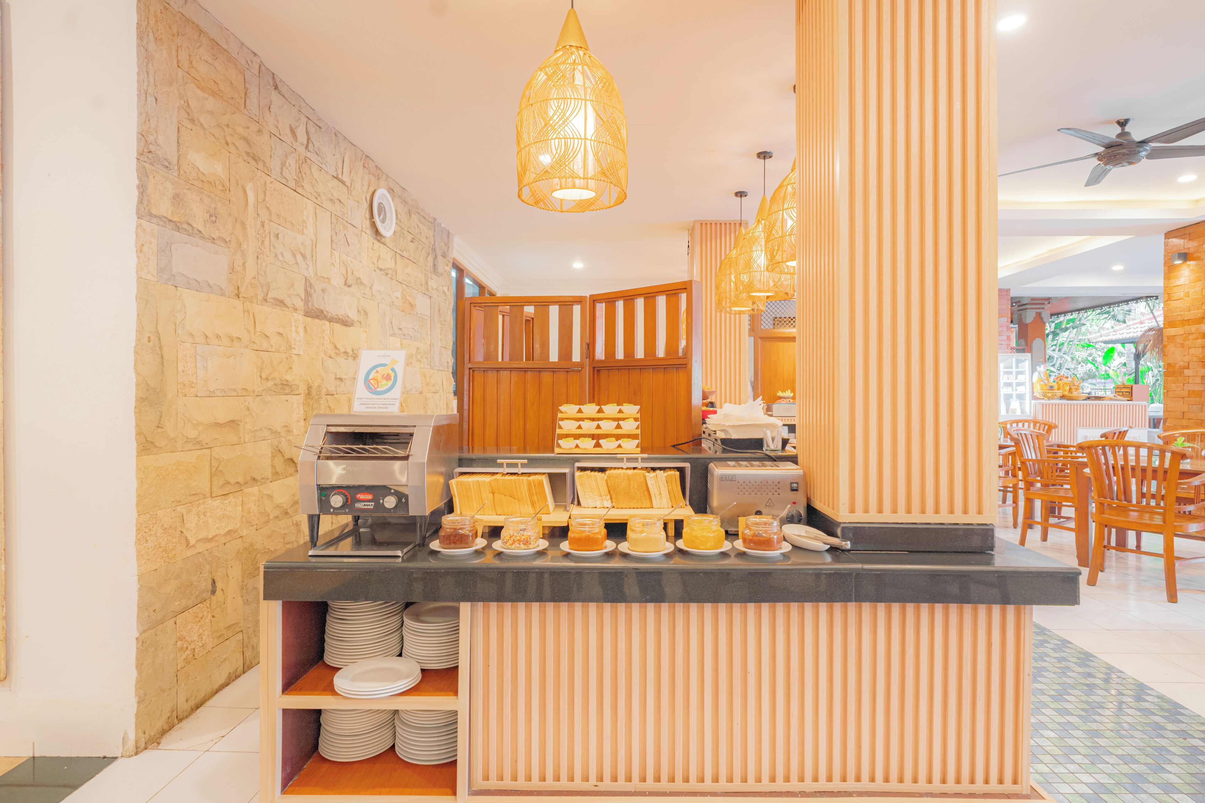 A breakfast bar with a stone wall backdrop, wooden paneling, and a ceiling fan.