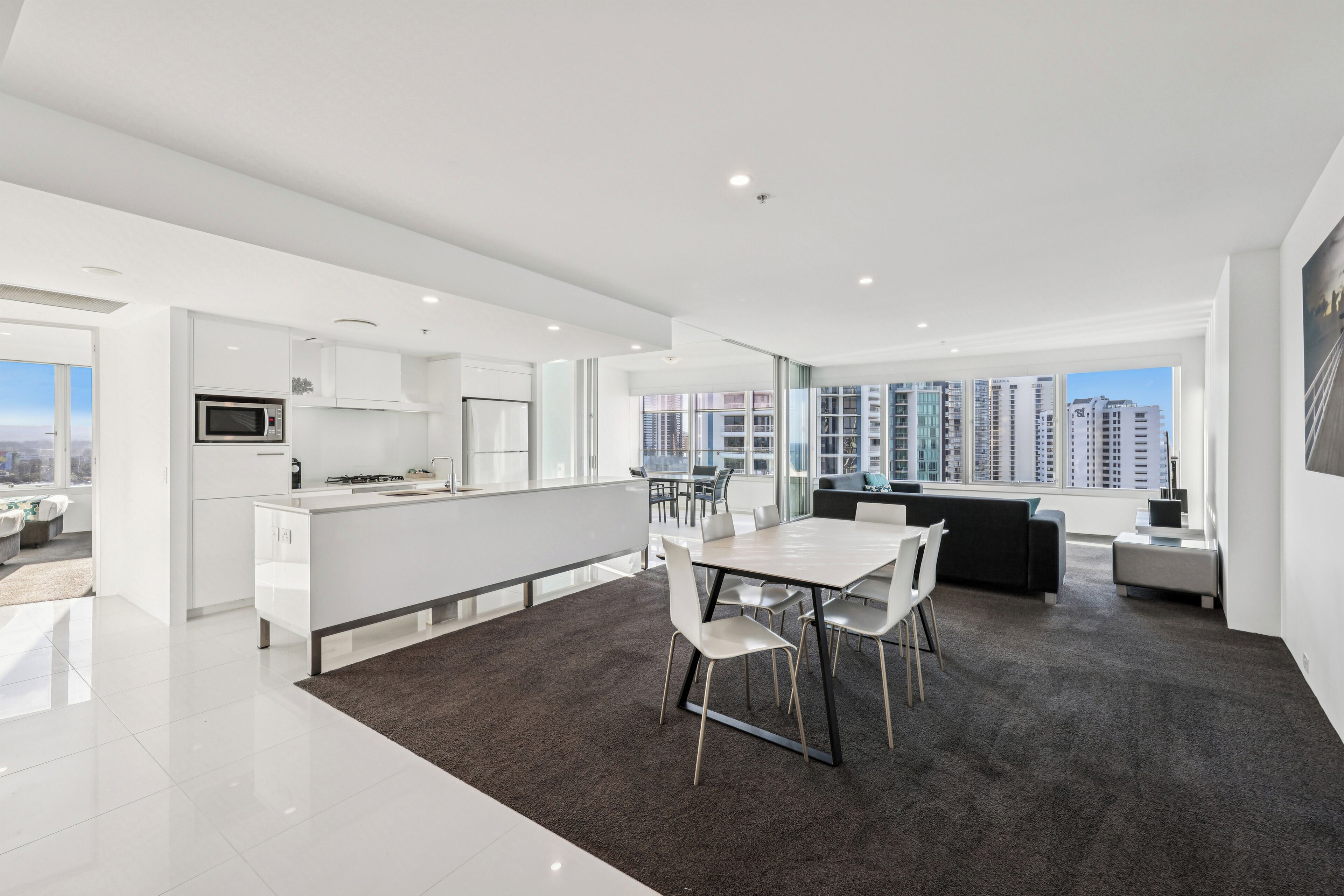 Un apartamento moderno con cocina, comedor y un amplio ventanal con vistas a un paisaje urbano.