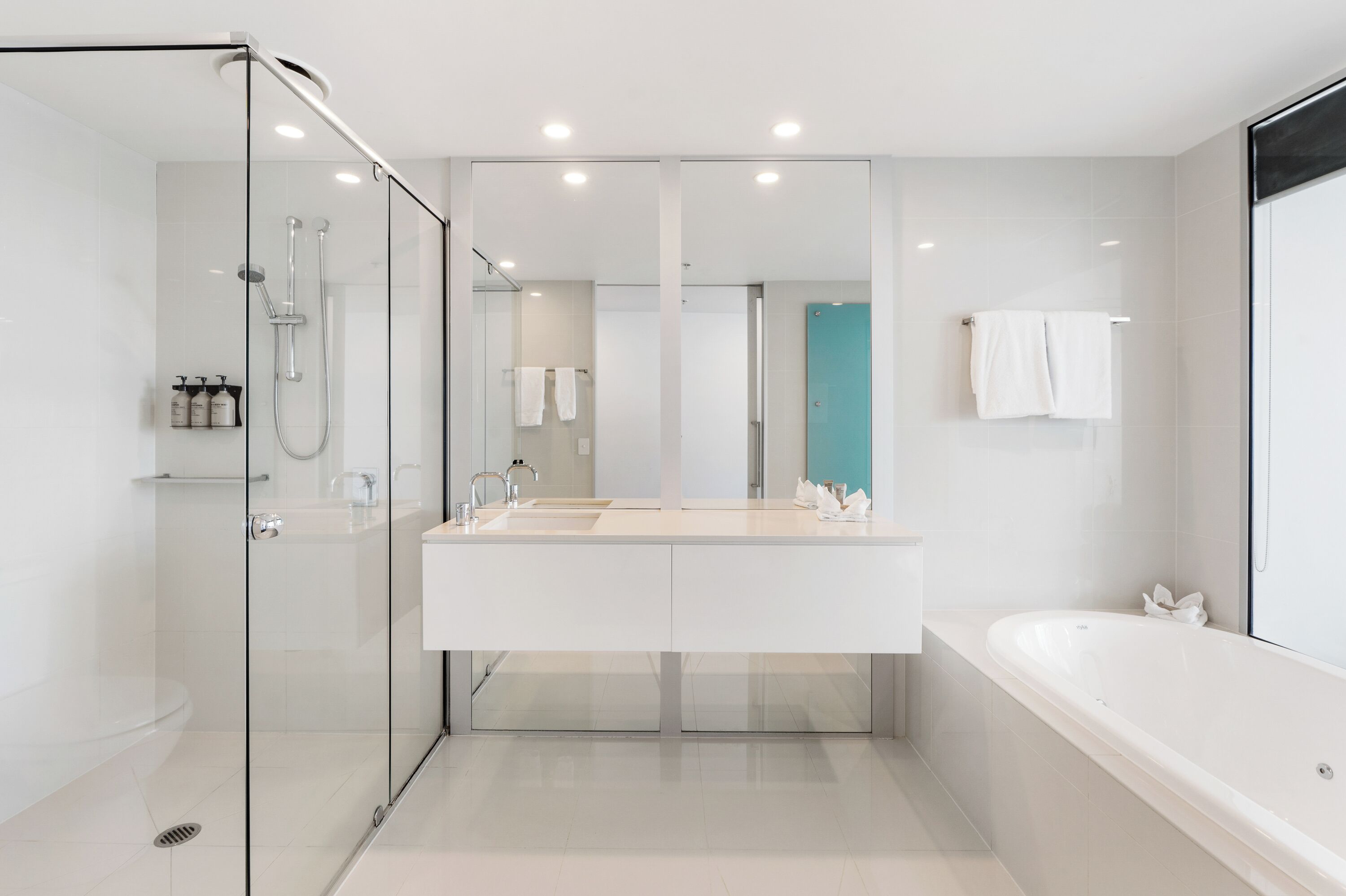 A modern bathroom with a glass-enclosed shower, a double sink vanity, and a standalone bathtub.