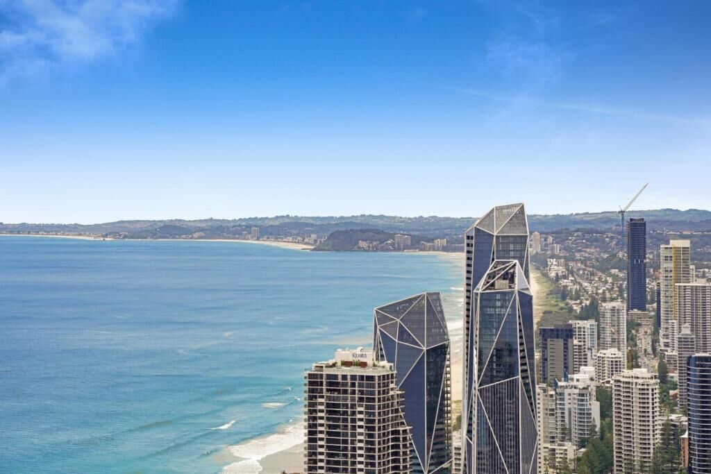 A coastal cityscape with modern skyscrapers, a beach, and a clear blue sky.