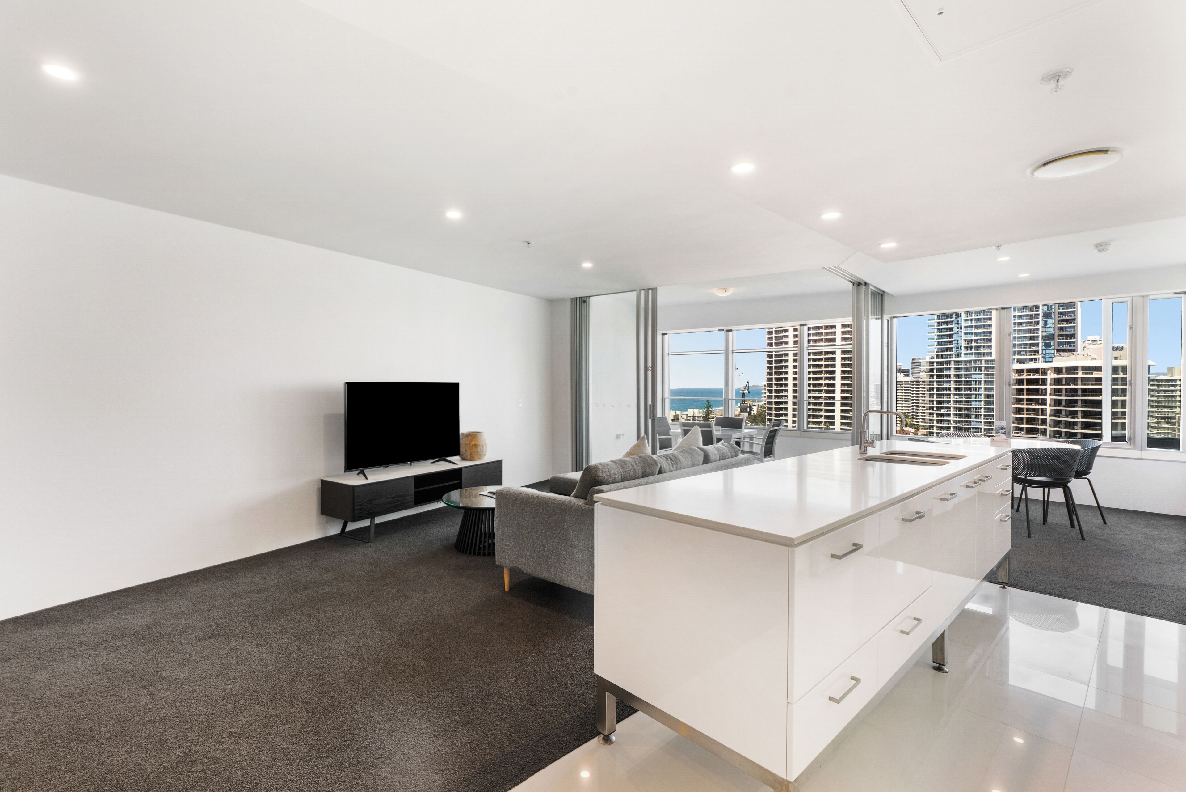 A modern living room with a large island, a flat-screen TV, and a sofa.