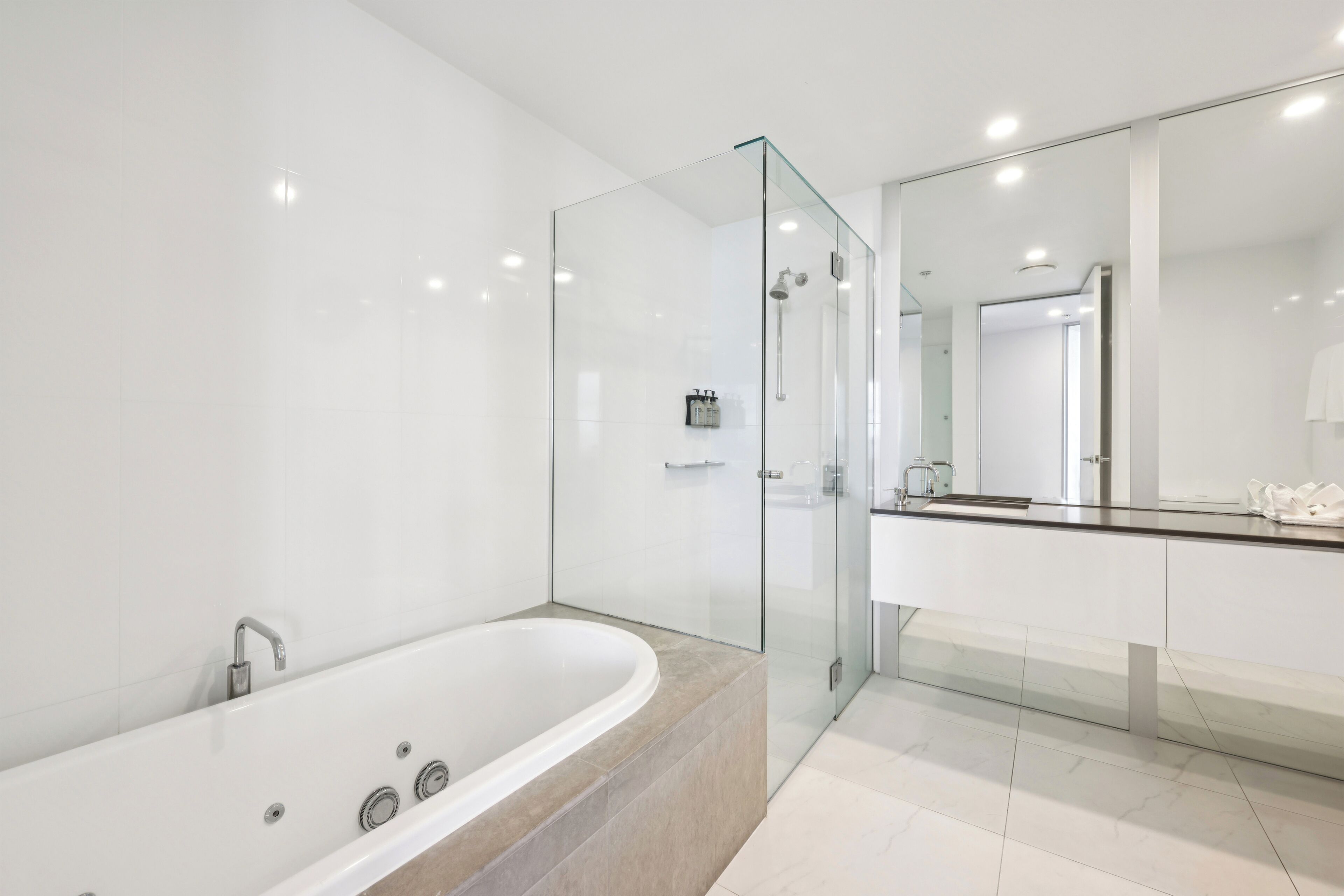 A modern bathroom with a glass-enclosed shower, a freestanding bathtub, and a large mirror.