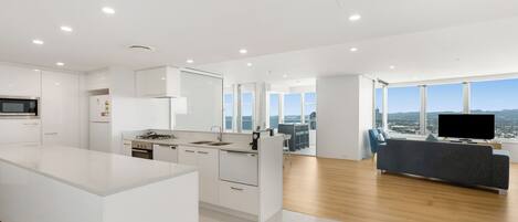 A modern kitchen with white cabinetry, a central island, and a large window overlooking a cityscape.
