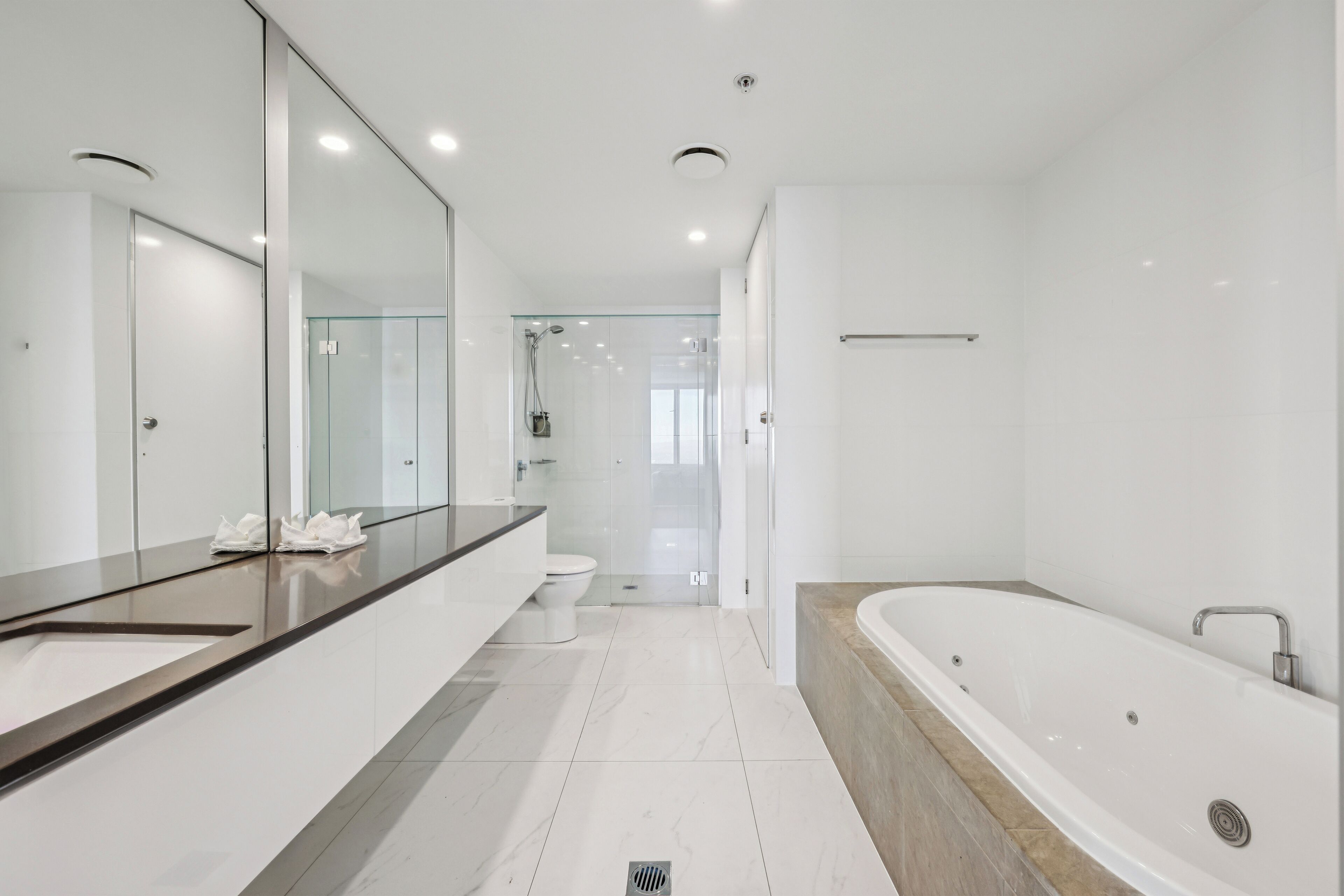Une salle de bain moderne avec un grand miroir, une baignoire et une douche à parois de verre.