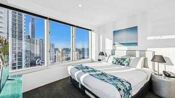 A modern hotel room with a large bed, a view of the city, and a cityscape through the window.