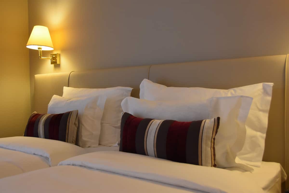 Une chambre d’hôtel avec un lit, des oreillers et une lampe fixée au mur.
