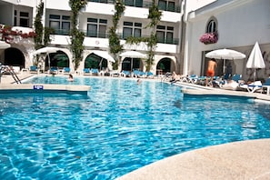 A swimming pool with clear blue water, surrounded by lounge chairs and umbrellas.