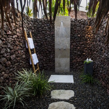 A stone-walled spa area with a wooden ladder, a water feature, and a small garden with plants.