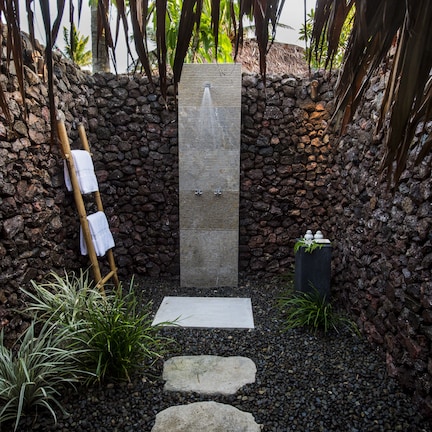 A stone-walled spa area with a wooden ladder, a water feature, and a small garden with plants.