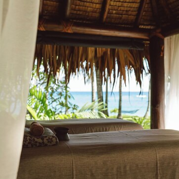 A room with a bed, a pillow, and a view of the ocean.