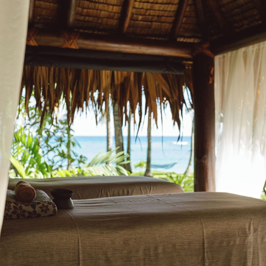 A room with a bed, a pillow, and a view of the ocean.