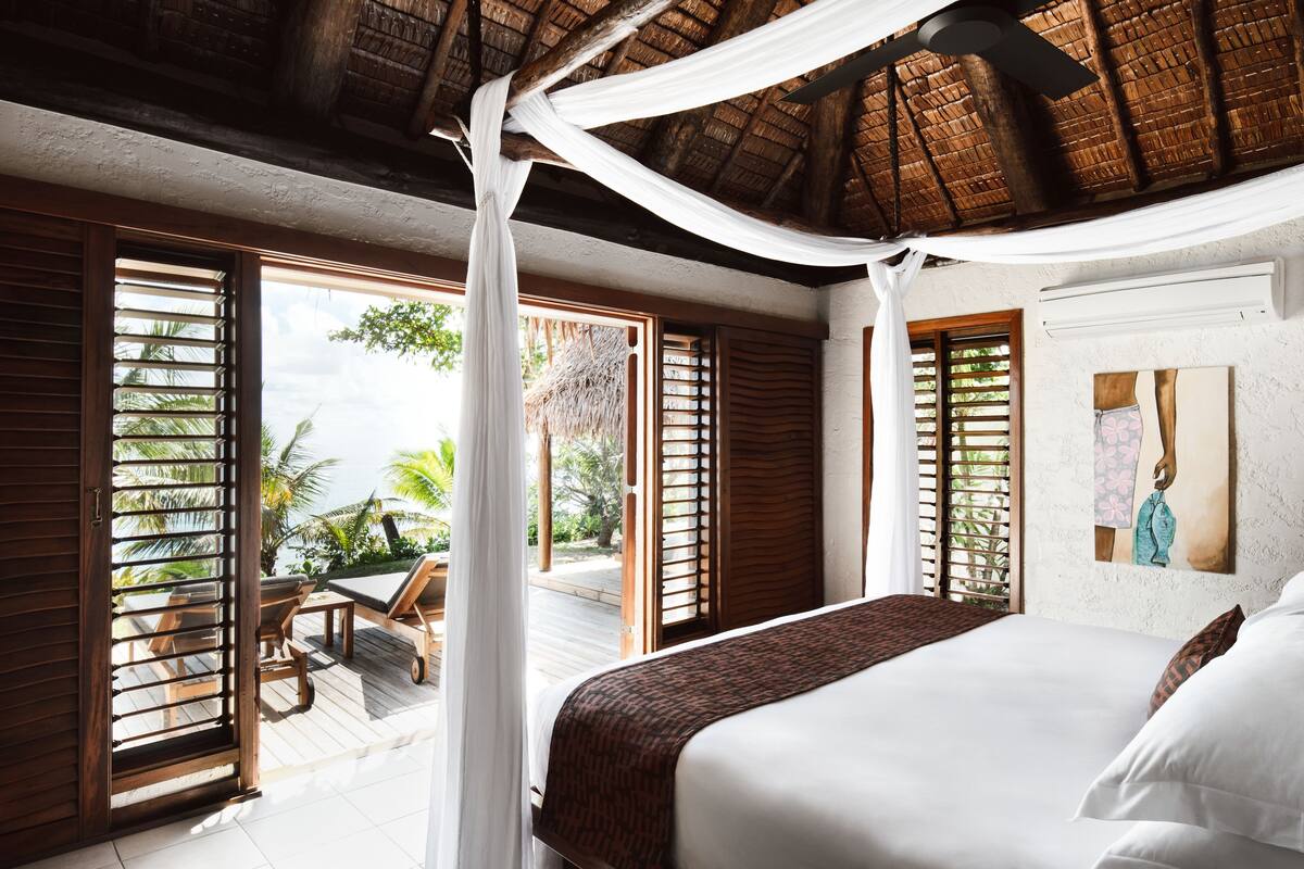 A bedroom with a bed, a ceiling fan, and a view of the outdoors.