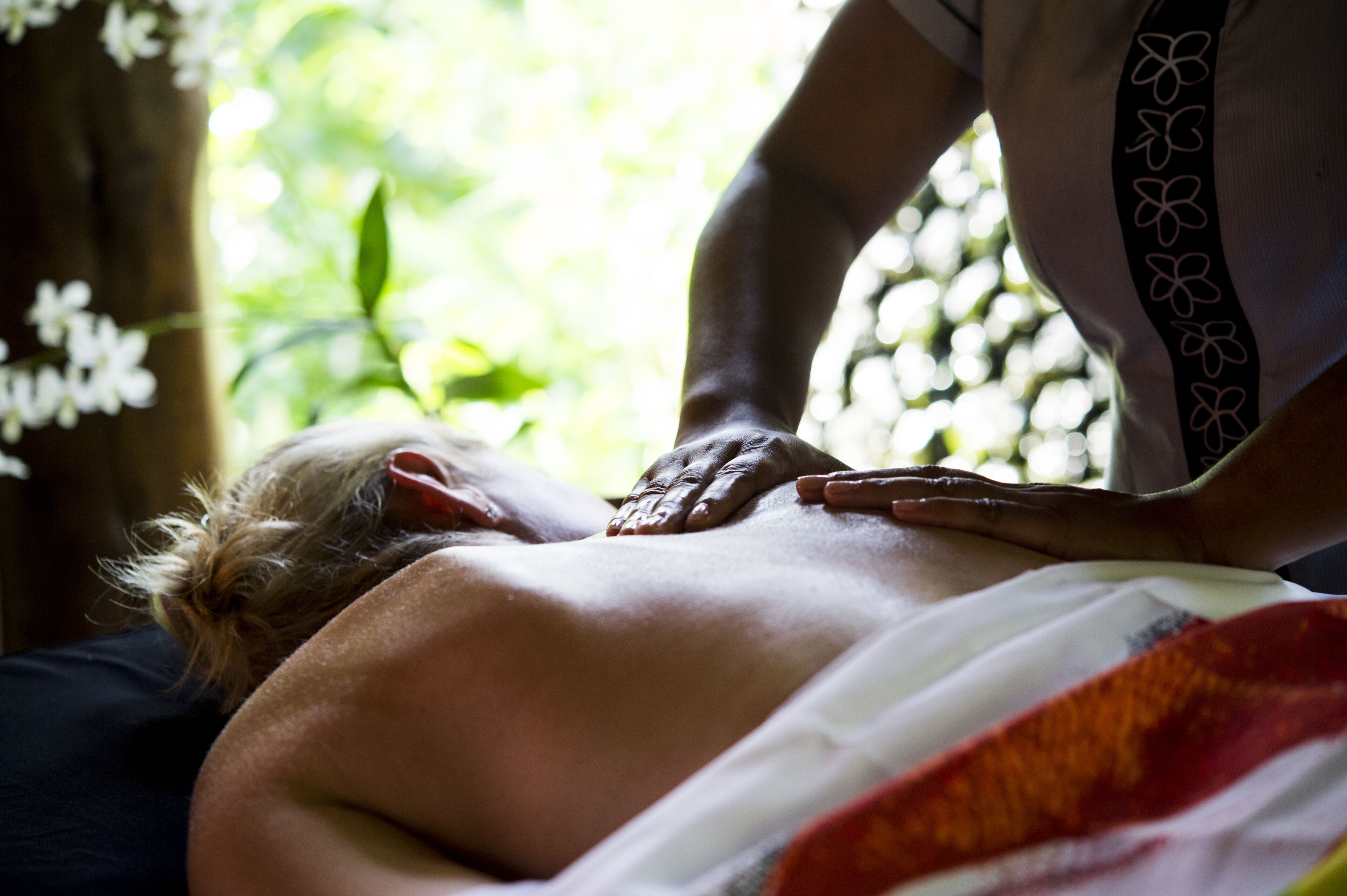 A massage therapy session in a room with a view of greenery.