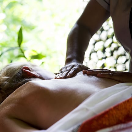 A massage therapy session in a room with a view of greenery.
