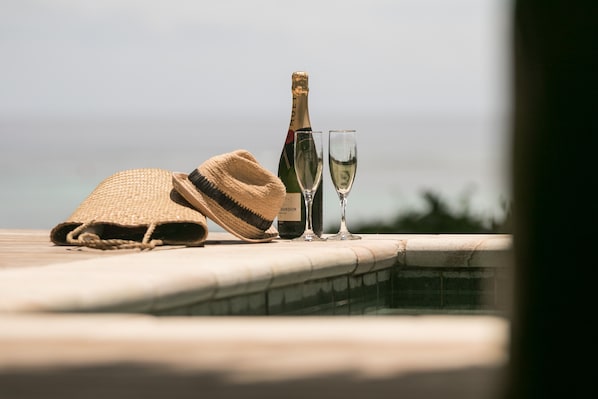 A bottle of champagne, two glasses, and a straw hat on a poolside ledge. - Tokoriki Island Resort - Adults only (Tokoriki Island)