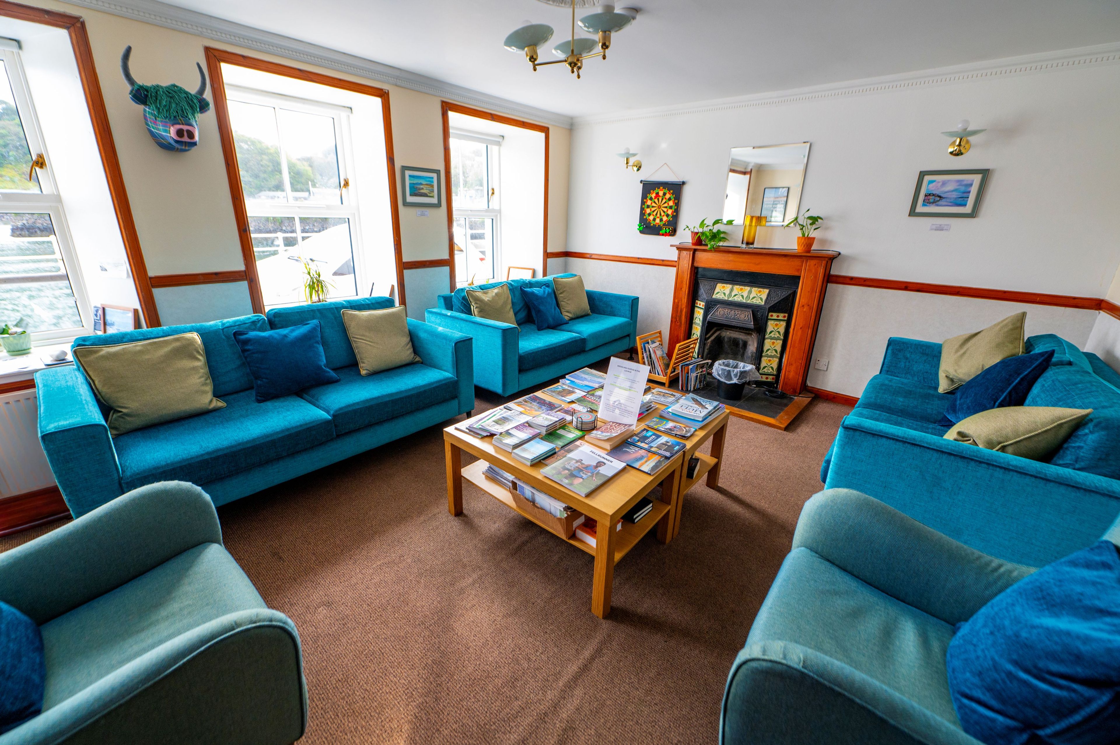 A living room with blue sofas, a coffee table with magazines, and a fireplace.