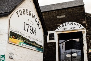 A sign for Tobermory Distillery, established in 1798, with a view of the entrance and a small window above the door. - Tobermory Youth Hostel (Isle of Mull)