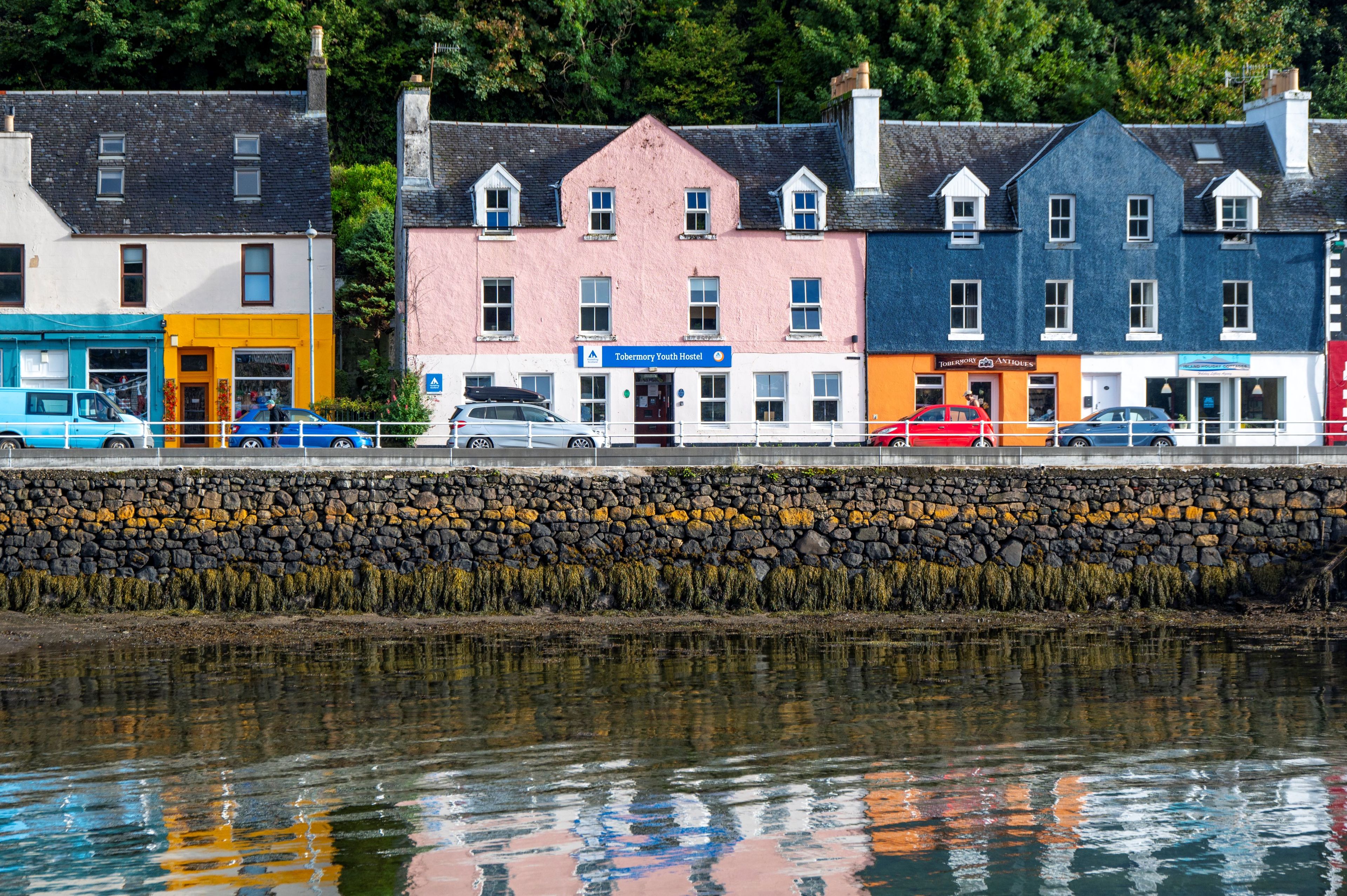 A waterfront view with a row of colorful buildings, including a youth hostel and an antiques shop.