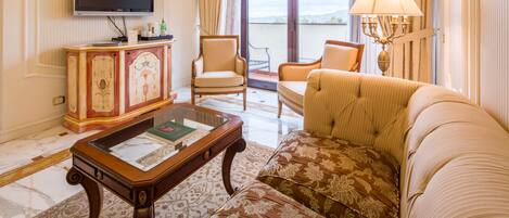 Una sala de estar con sofá, sillones, una mesa de centro, televisor y vistas al exterior.