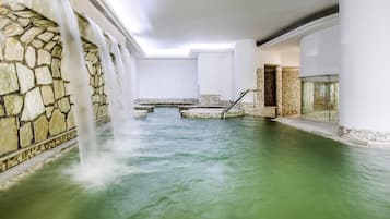 Un'area spa con parete in pietra, elemento d'acqua e porta in vetro.