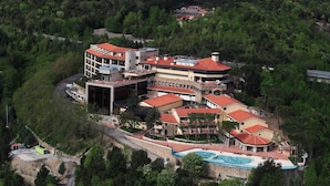 A large, multi-story building with a swimming pool, surrounded by lush greenery. - Mercure Petriolo Siena Terme Spa Hotel (Civitella Paganico)
