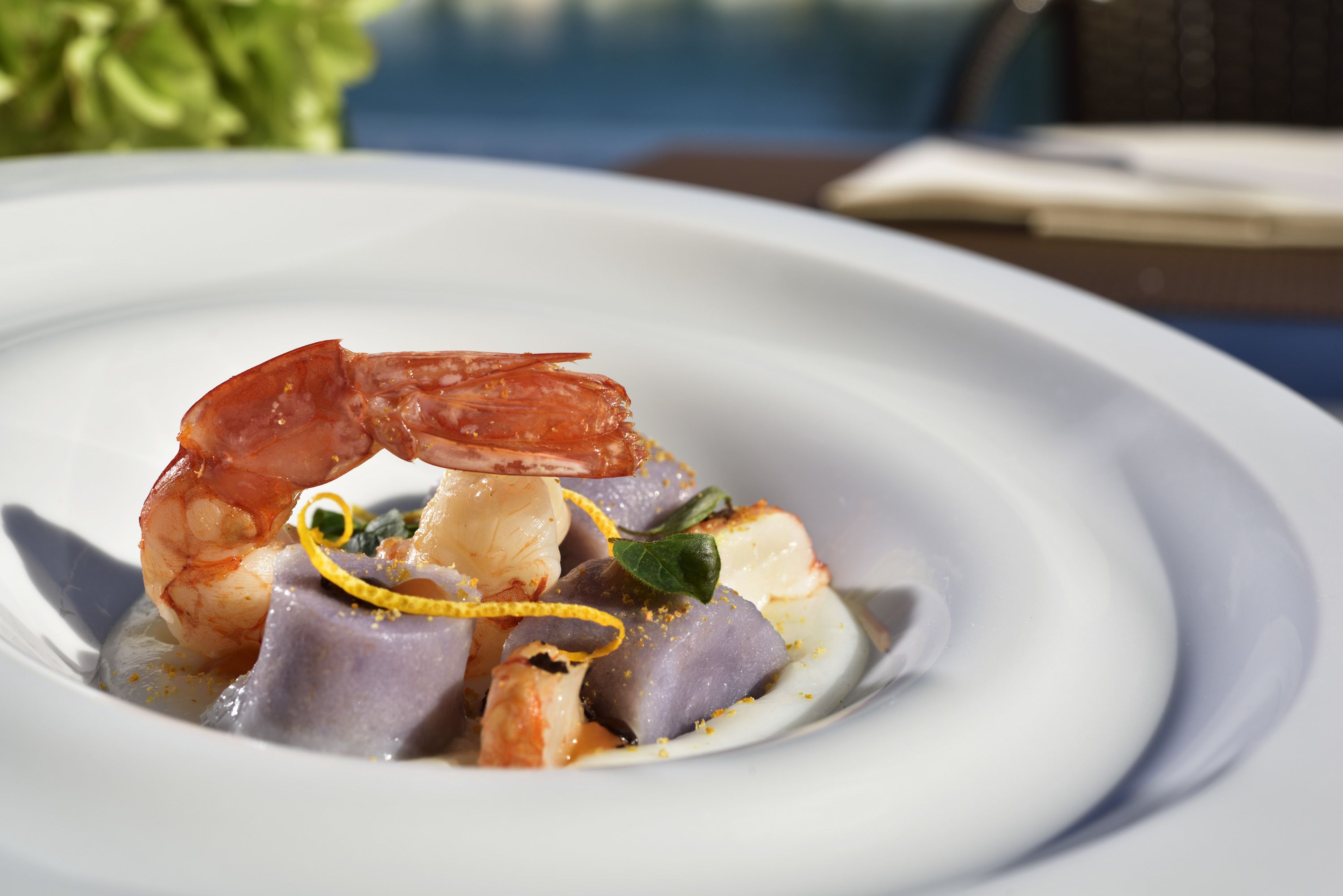 Un plat de fruits de mer avec une crevette, servi dans une assiette blanche.