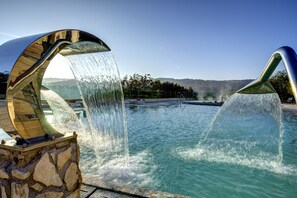 Une piscine dotée d’un élément décoratif aquatique moderne et d’une structure en pierre.