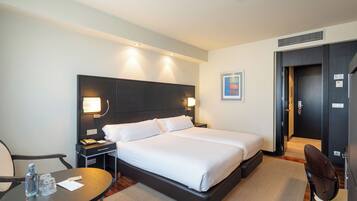 Ein Hotelzimmer mit einem großen Bett, Nachttischen, einem Schreibtisch und einem Sessel.