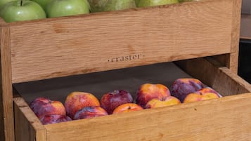 A wooden fruit display with green apples, pears, plums, and bananas.