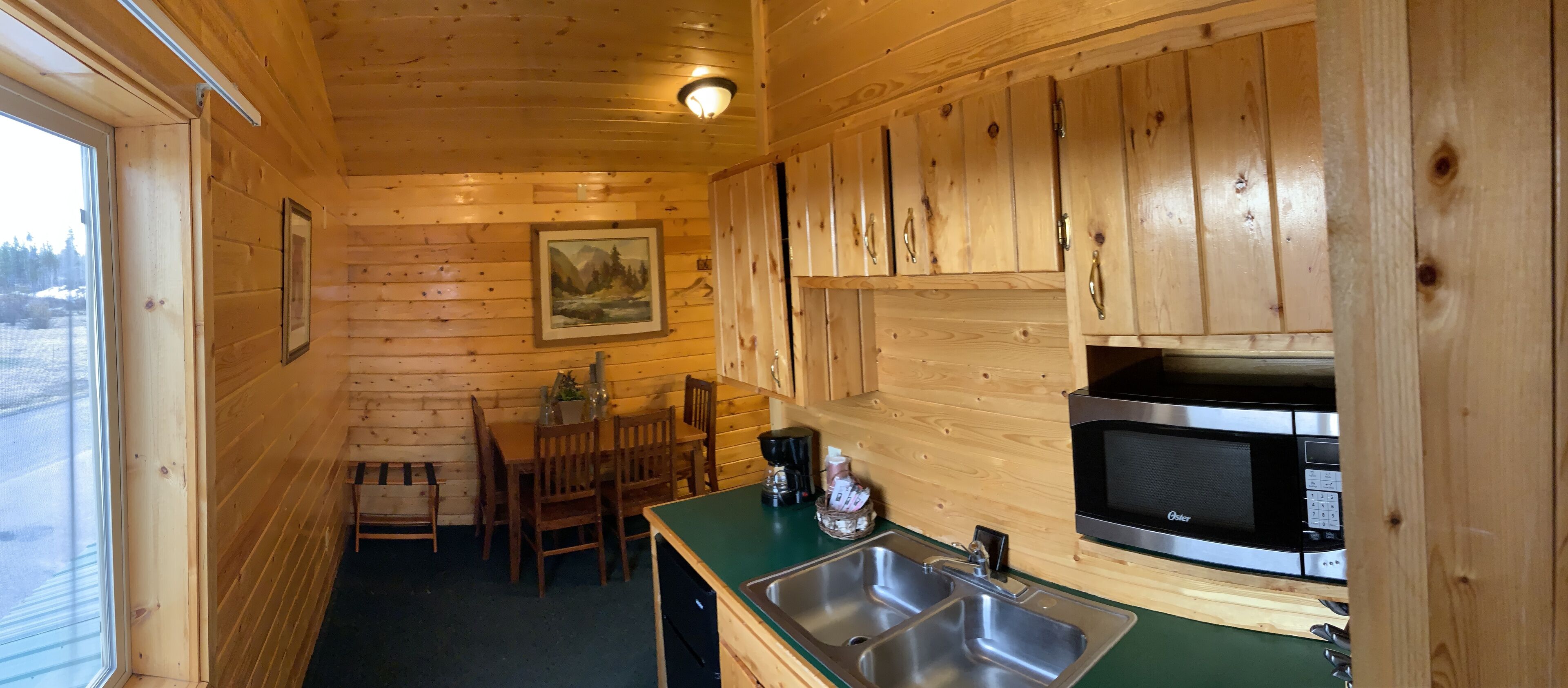 A wooden cabin interior with a dining area, a sink, and a microwave.