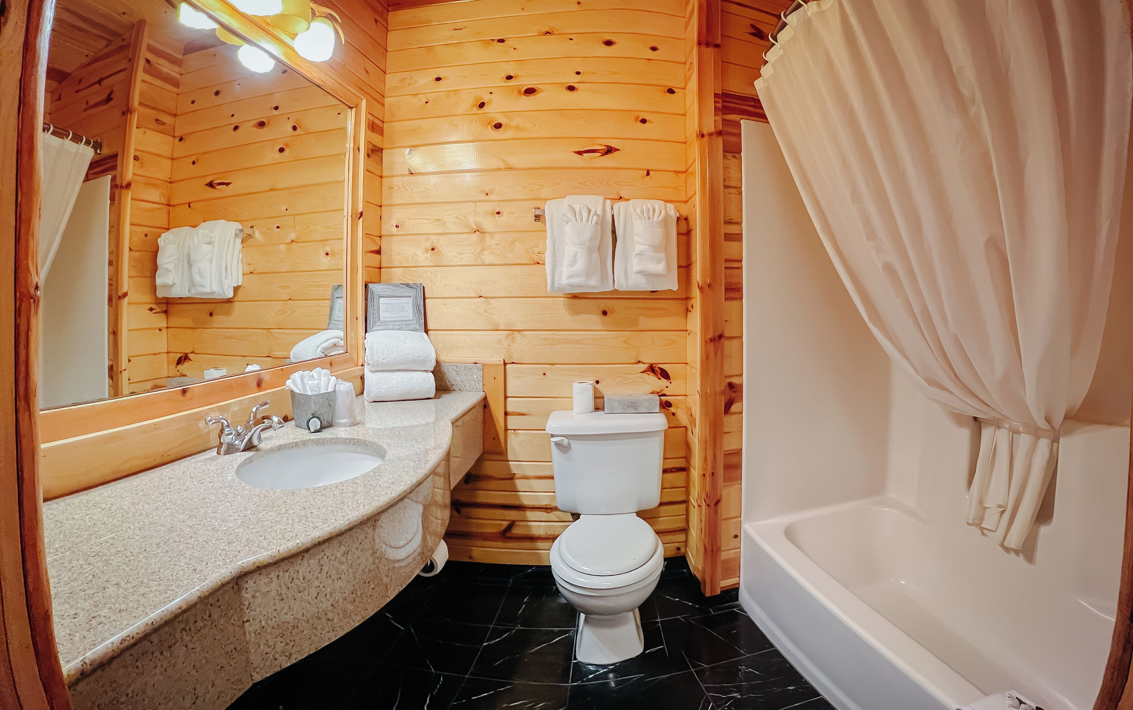 A wooden cabin bathroom with a sink, toilet, and bathtub.