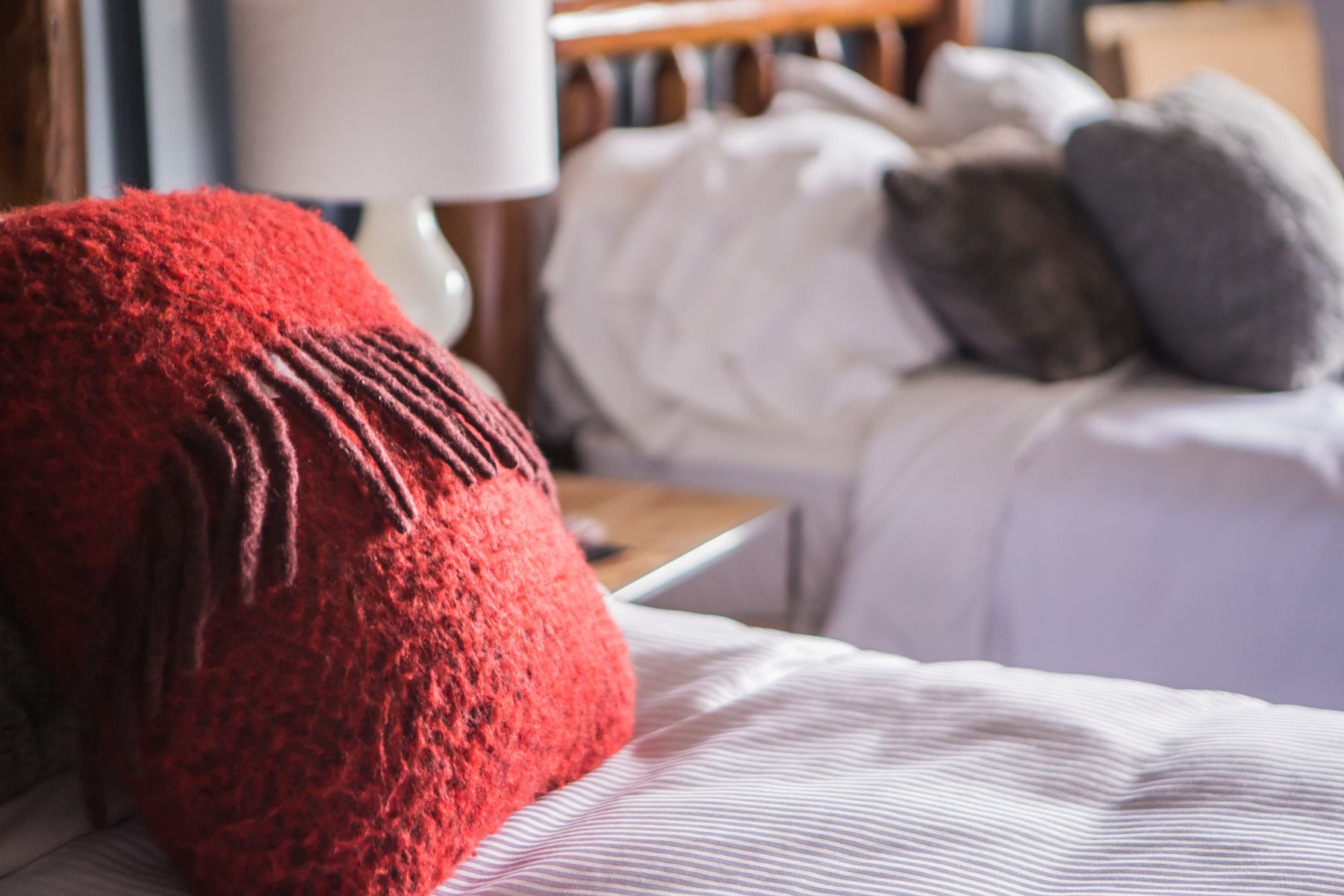 A bed with a red pillow and a striped blanket.