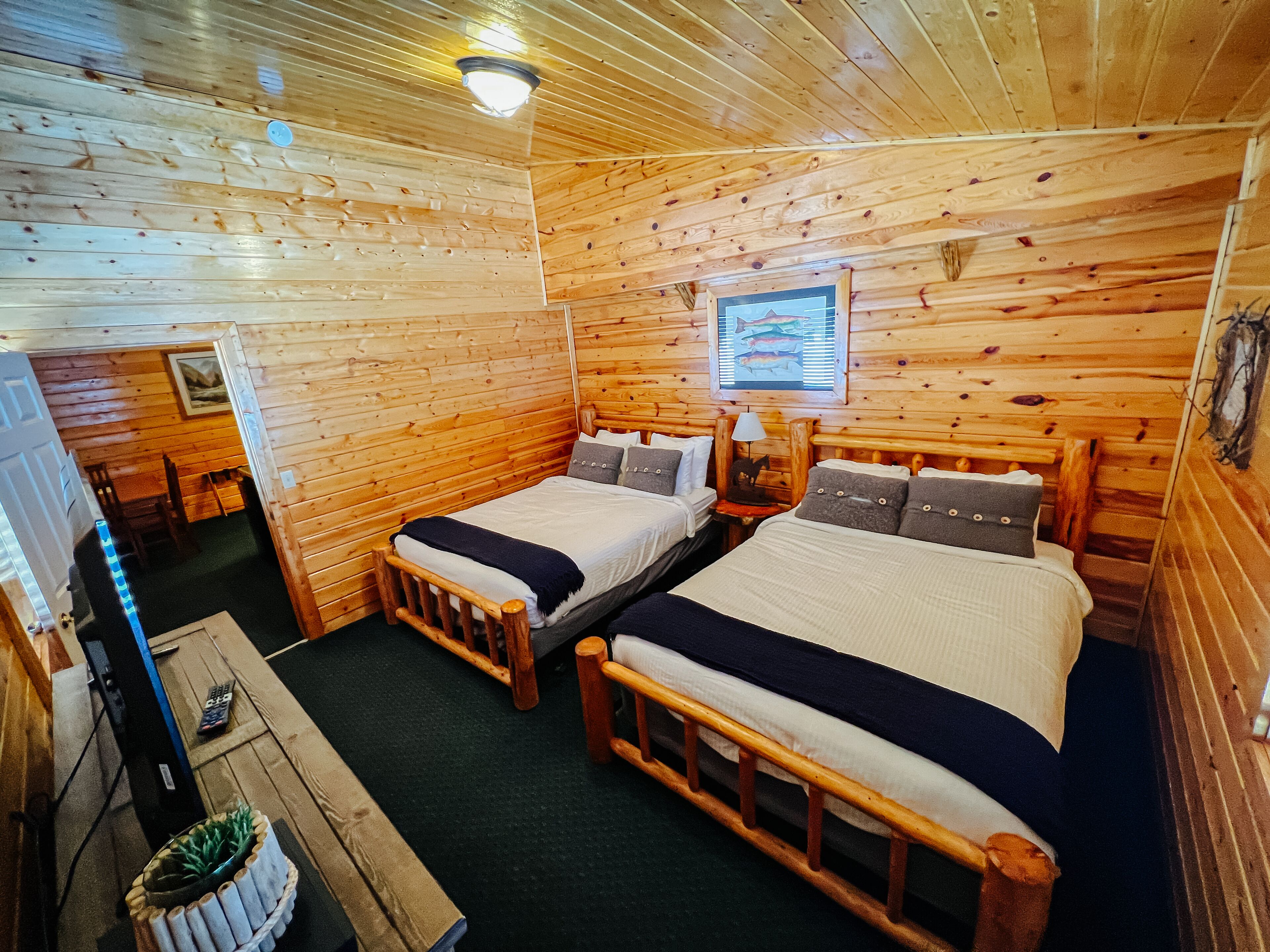 A cabin with two wooden beds, a small table, and a television.