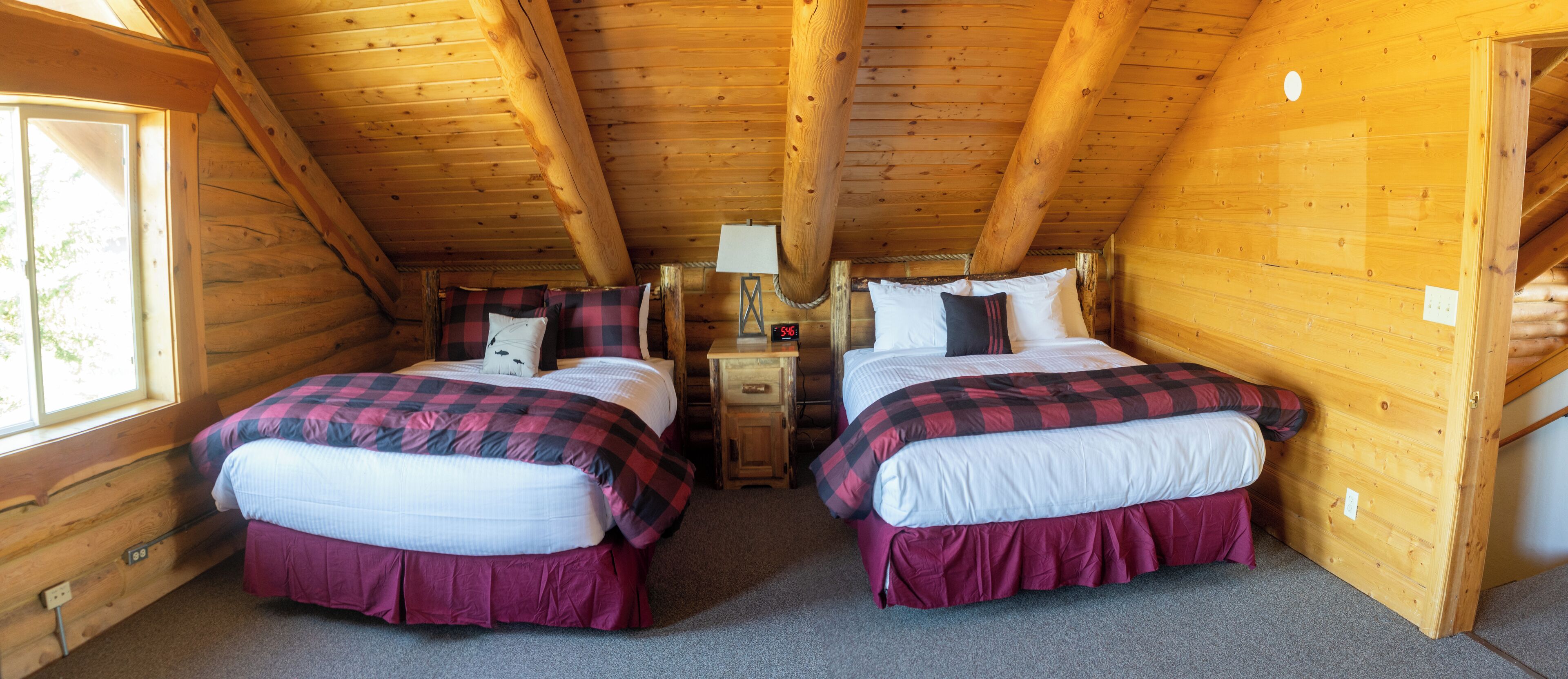 A cabin with two beds, a nightstand, a lamp, and a window.